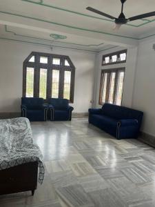 a living room with two blue couches and two windows at Aura house in Jorhat