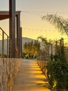 a wooden walkway next to a building with mountains in the background at Valle Soléa in Valle de Guadalupe