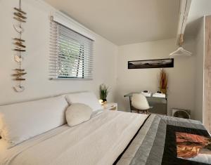 a bedroom with a white bed and a desk at Turtle Cabin in Papamoa