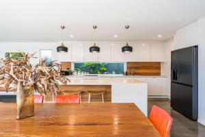 a kitchen with a wooden table with orange chairs at Beachside Banksia in East Ballina