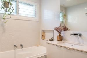 a white bathroom with a tub and a sink at Beachside Banksia in East Ballina +14 photos
