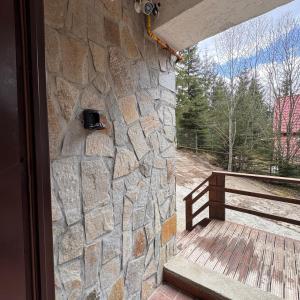 a stone wall next to a porch with a window at Ap DoDe Predeal in Predeal