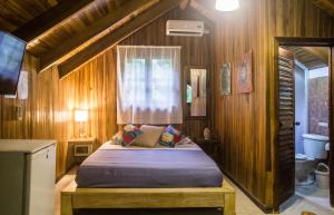 1 dormitorio con 1 cama en una habitación de madera en Santascabinas, en Santa Teresa Beach