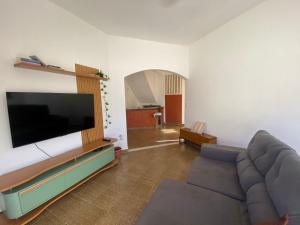 a living room with a couch and a flat screen tv at Casa para a temporada com 3 quartos a caminho do centro in Porto Seguro