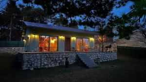 a small house with a stone wall at night at Uludag ztrk Mountain House in Kirazlı
