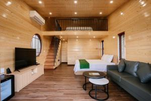 a room with a bed and a couch and a tv at Bai Tu Long Mountain Resort in Hà Cái