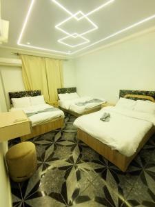 a room with three beds and a table and chairs at Kemet Pyramids Apartments in Cairo