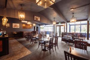 a dining room with tables and chairs and windows at The Halswell in Christchurch