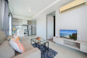 a living room with a couch and a flat screen tv at Surin Condo Walk to Beach with Rooftop Pool - C416 in Ban Lum Fuang