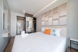 a bedroom with a large white bed with orange pillows at Surin Condo Walk to Beach with Rooftop Pool - C416 in Ban Lum Fuang +9 photos