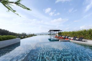 an infinity pool with chairs and a table on a building at Surin Condo Walk to Beach with Rooftop Pool - C416 in Ban Lum Fuang