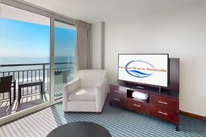 a living room with a television and a balcony at Modern Decor Stunning Ocean View Condo Sleeps 8 in Myrtle Beach +72 photos