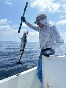 Ein Mann hält einen Fisch mit einem Paddel auf einem Boot in der Unterkunft Shitha Inn in Hithadhoo