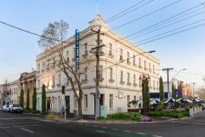 a large white building with a blue sign on it at Middle Park Hotel in Melbourne