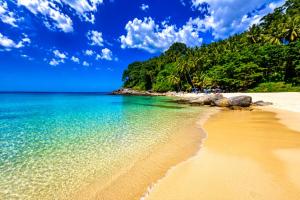 a beach with rocks and the water and trees at Surin Condo Walk to Beach with Rooftop Pool - C416 in Ban Lum Fuang
