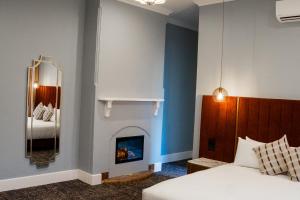 a bedroom with a fireplace and a bed and a mirror at Kincraig Hotel in Naracoorte