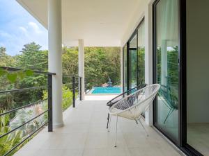 a balcony with a chair and a swimming pool at Tropical Sea View 2Br Private Pool Villa in Plai Laem