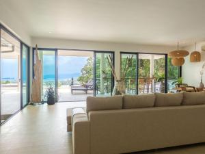 a living room with a couch and glass doors at Tropical Sea View 2Br Private Pool Villa in Plai Laem