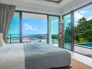 a bedroom with a large bed and large windows at Tropical Sea View 2Br Private Pool Villa in Plai Laem