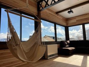 a hammock hanging in a room with windows at KONAYUKI Apartment in Myoko