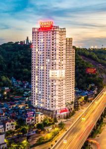 a tall white building with a neon sign on top of it at Ha Long 2BR Apartment - Spacious & Modern - Near Center in Ha Long