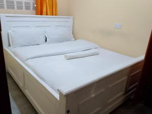 two beds in a room with white sheets and pillows at Mwembe Airbnbs in Kisii