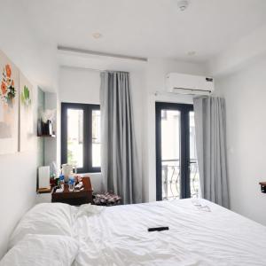a bedroom with a white bed and two windows at ICHI Home Kim Long in Hue +10 photos