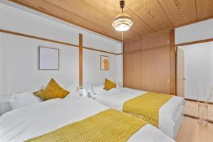 two beds in a room with white and yellow sheets at Crystal Jade Awaza2-4F in Wada