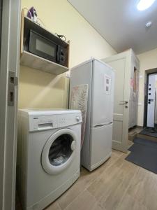 a laundry room with a washer and a refrigerator at Apart Rooms & Hostel 5 Capsule Rooms in Ustʼ-Kamenogorsk