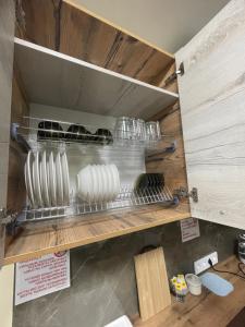 a kitchen with a shelf with dishes on it at Apart Rooms & Hostel 5 Capsule Rooms in Ustʼ-Kamenogorsk