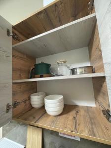 a kitchen with wooden shelves with pots and pans at Apart Rooms & Hostel 5 Capsule Rooms in Ustʼ-Kamenogorsk