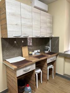 a kitchen with a wooden counter with chairs and cabinets at Apart Rooms & Hostel 5 Capsule Rooms in Ustʼ-Kamenogorsk +20 photos