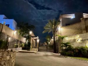 a building with a gate and a palm tree at night at Casa Boho - Heated Pool, Private Grill & Garden - Xochitepec in Tezoyuca