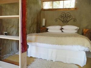 een slaapkamer met een bed met witte kussens en een raam bij El Cielo Lodge in San José de Maipo