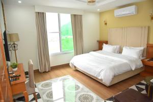 a bedroom with a white bed and a large window at River View Hotel in Heart of Muzaffarabad,213 in Muzaffarabad