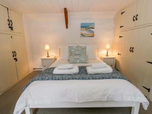 a bedroom with a large white bed with two lamps at Fern Cottage in Cardigan
