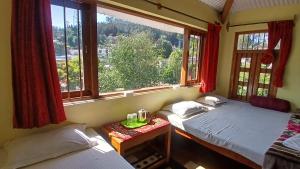 two beds in a room with a window at Satya Anand Pure Veg and Non Alcoholic Cottage in Coonoor