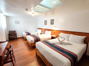 a hotel room with two beds and a desk and a table at Saphi Inn Cusco - Excelente ubicación in Cusco