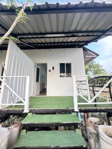 a small white house with a green porch with a bench at Summer Sunshine in Songkhla