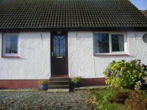 Casa blanca con puerta y ventanas azules en Sonas, Dunans, en Flodigarry