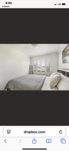 a white bedroom with a bed and two windows at 3 Mile in Lennox Head