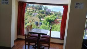 a dining room with a table and a large window at Satya Anand Pure Veg and Non Alcoholic Cottage in Coonoor