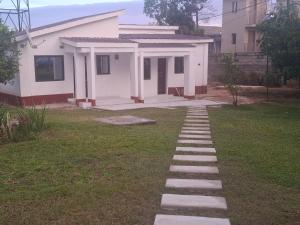 a walkway leading to a white house at Rose's Garden Cottages in Lusaka