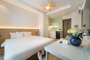a bedroom with a bed and a table with a vase of flowers at Nina Sky Serviced Apartment in Ho Chi Minh City