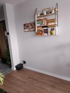 a room with a white wall with a shelf with books at Jolanta's apartment in Hajnówka
