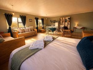 a bedroom with a large bed and a living room at At the Indi in Struisbaai