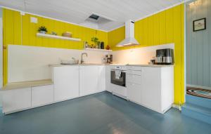 a kitchen with white cabinets and yellow walls at Nice Home In Risør With House Sea View in Risør