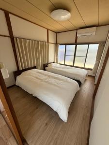 a bedroom with two beds and a large window at Izu-Nagaoka Base in Kona