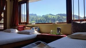 two beds in a room with a large window at Satya Anand Pure Veg and Non Alcoholic Cottage in Coonoor