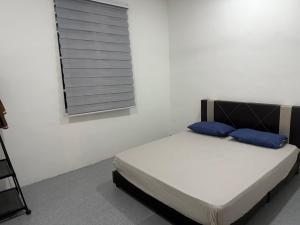 a bed with blue pillows in a room with a window at DF Homestay in Kangar